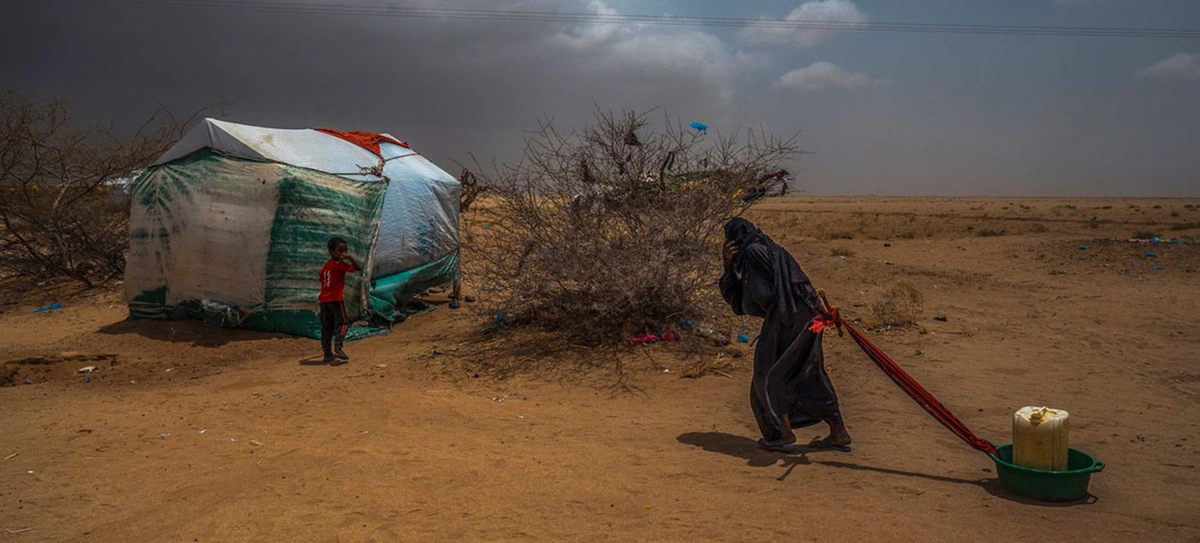 Idosa leva água para sua tenda em um campo de deslocados no norte do Iêmen, perto da fronteira com a Arábia Saudita