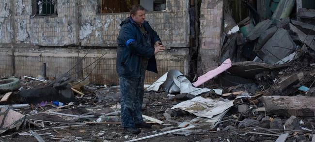 Um homem remove detritos ao redor de um prédio residencial em Kiev, na Ucrânia.