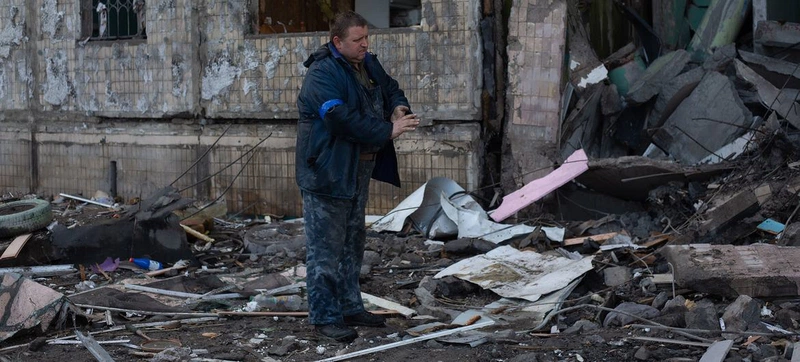 Um homem remove detritos ao redor de um prédio residencial em Kiev, na Ucrânia.