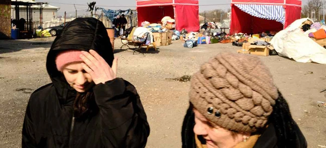 Mulheres ucranianas caminham em frente a tendas montadas em Medyka, na Polônia, para ajudar refugiados que fogem do conflito