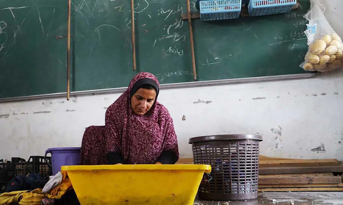 Uma mulher palestina deslocada lava as roupas de sua família em uma sala de aula em um abrigo da Unrwa em Khan Younis, no sul de Gaza.